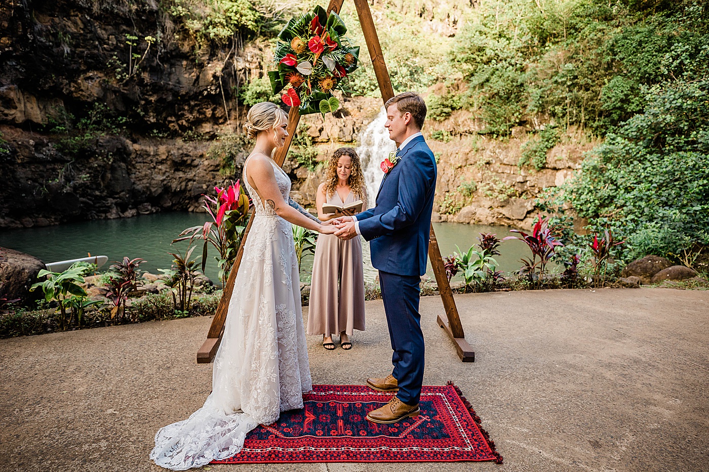 Bride and groom standing in front of family on benches at Waimea Valley wedding.