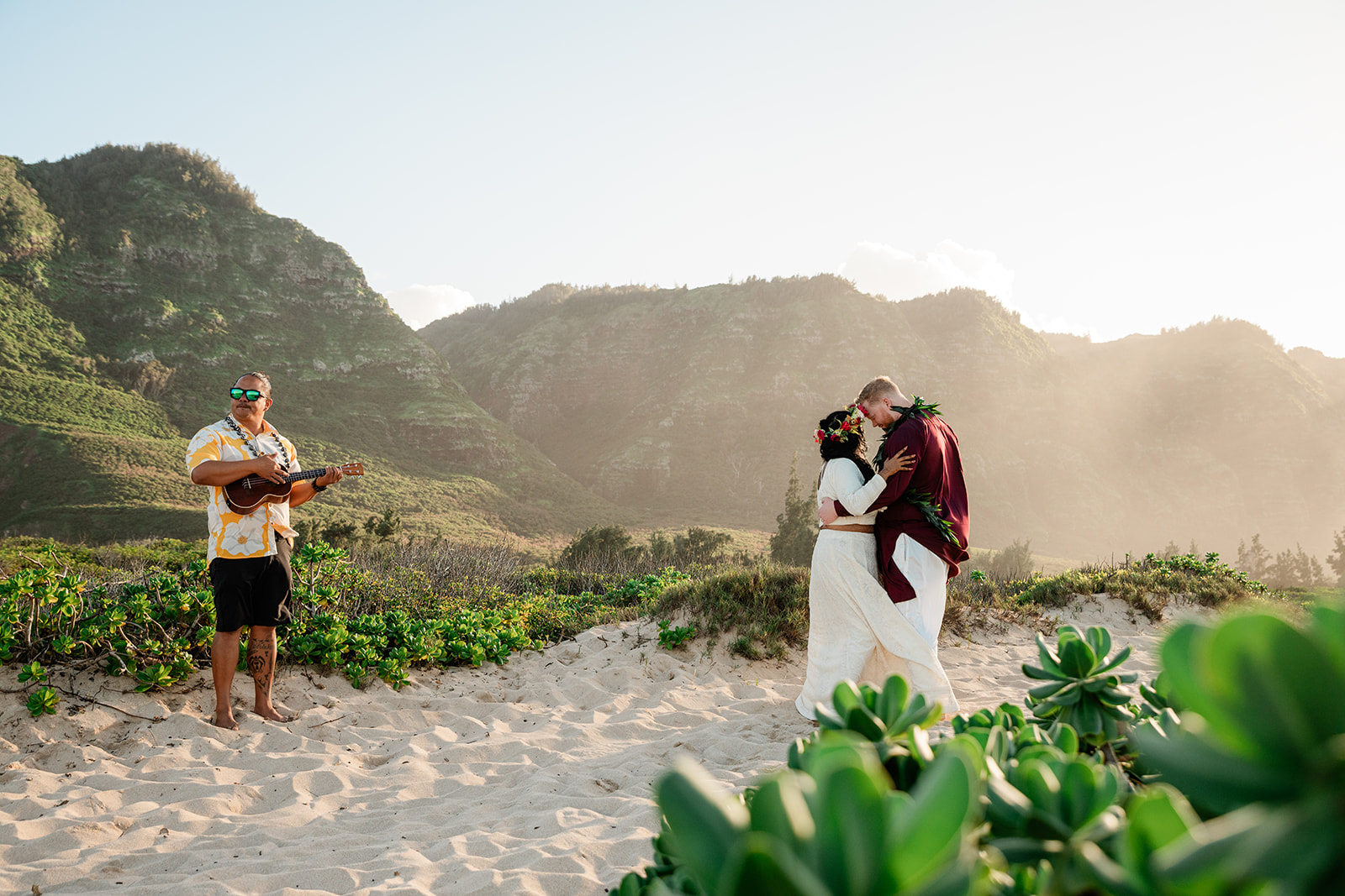 Couple exchanging vows during their all-inclusive elopement ceremony on a Hawaiian beach with sunset light
