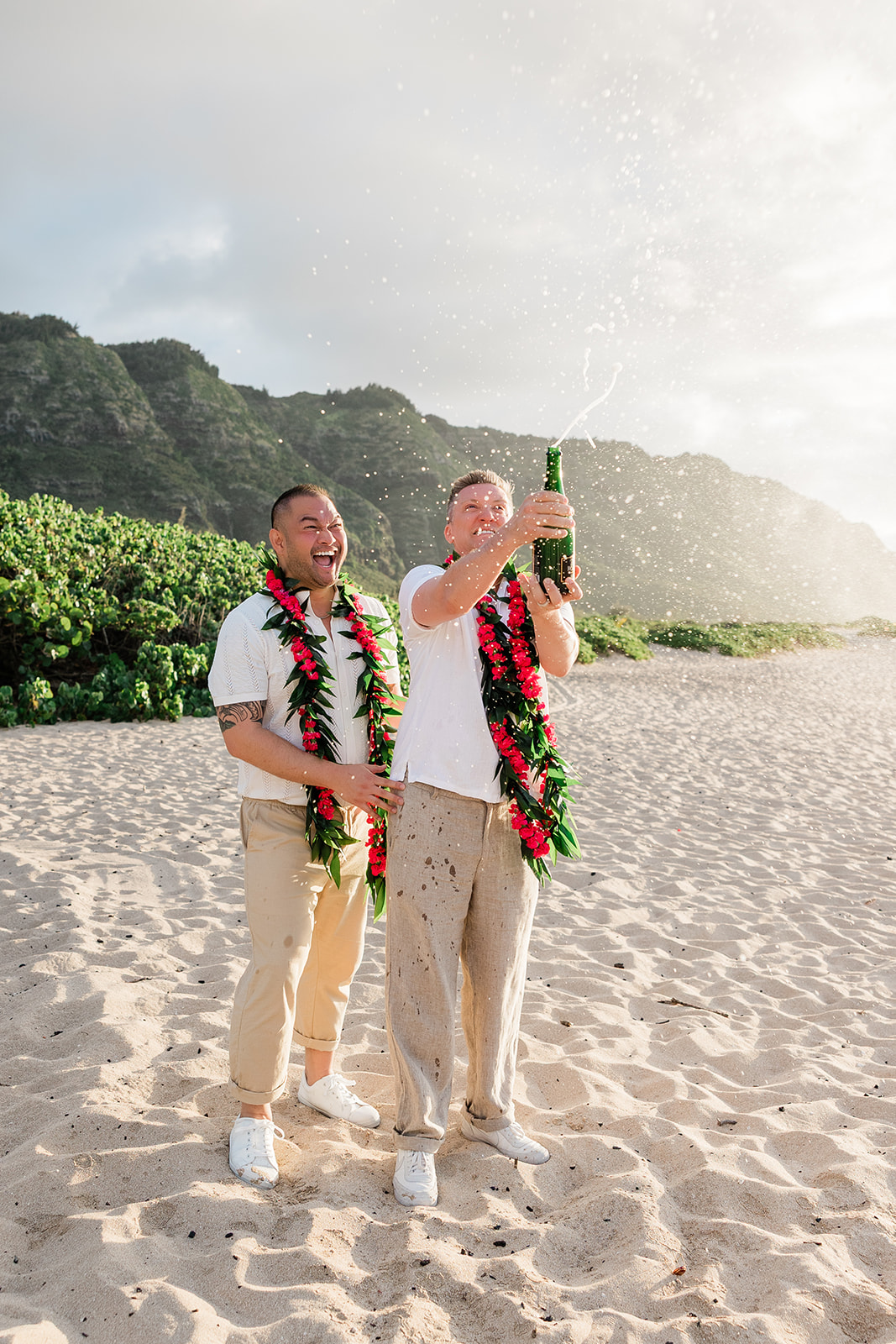 Two grooms celebrating with champagne after their LGBTQ+ friendly elopement in Hawaii