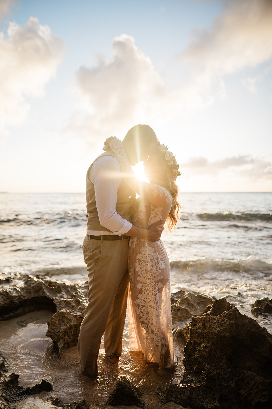 Couple sharing a kiss with the warm sunset glowing between them during their Oahu elopement photography session