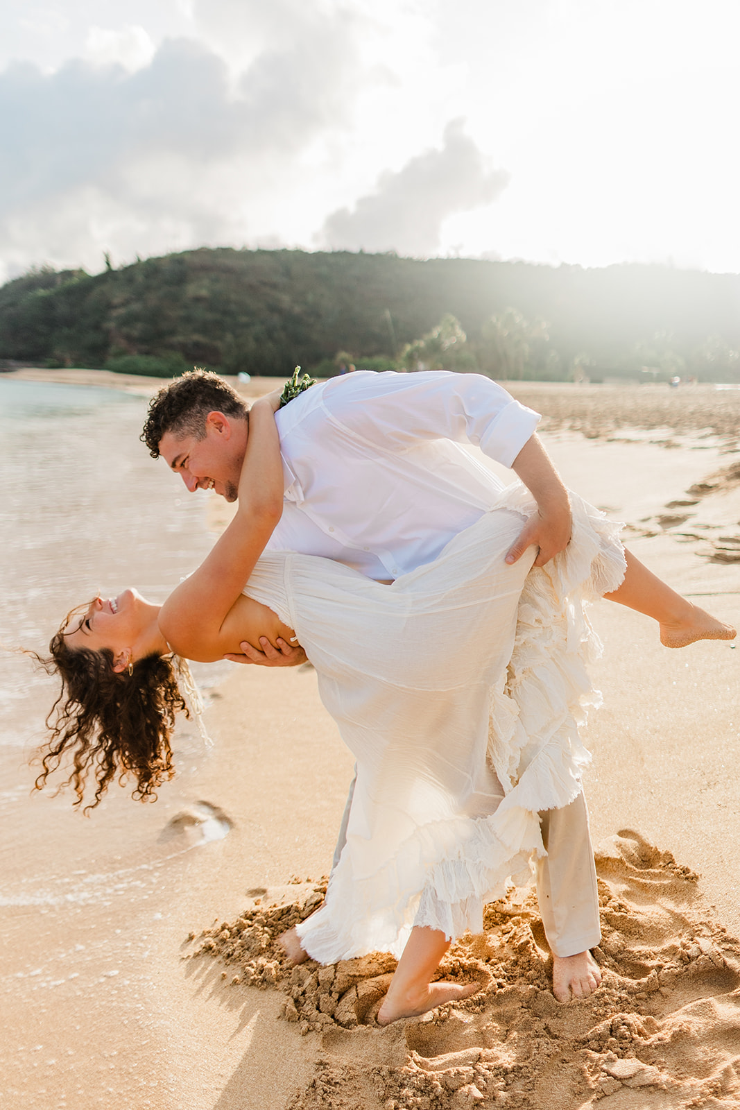 Groom dipping his bride on the beach during a romantic Oahu elopement.