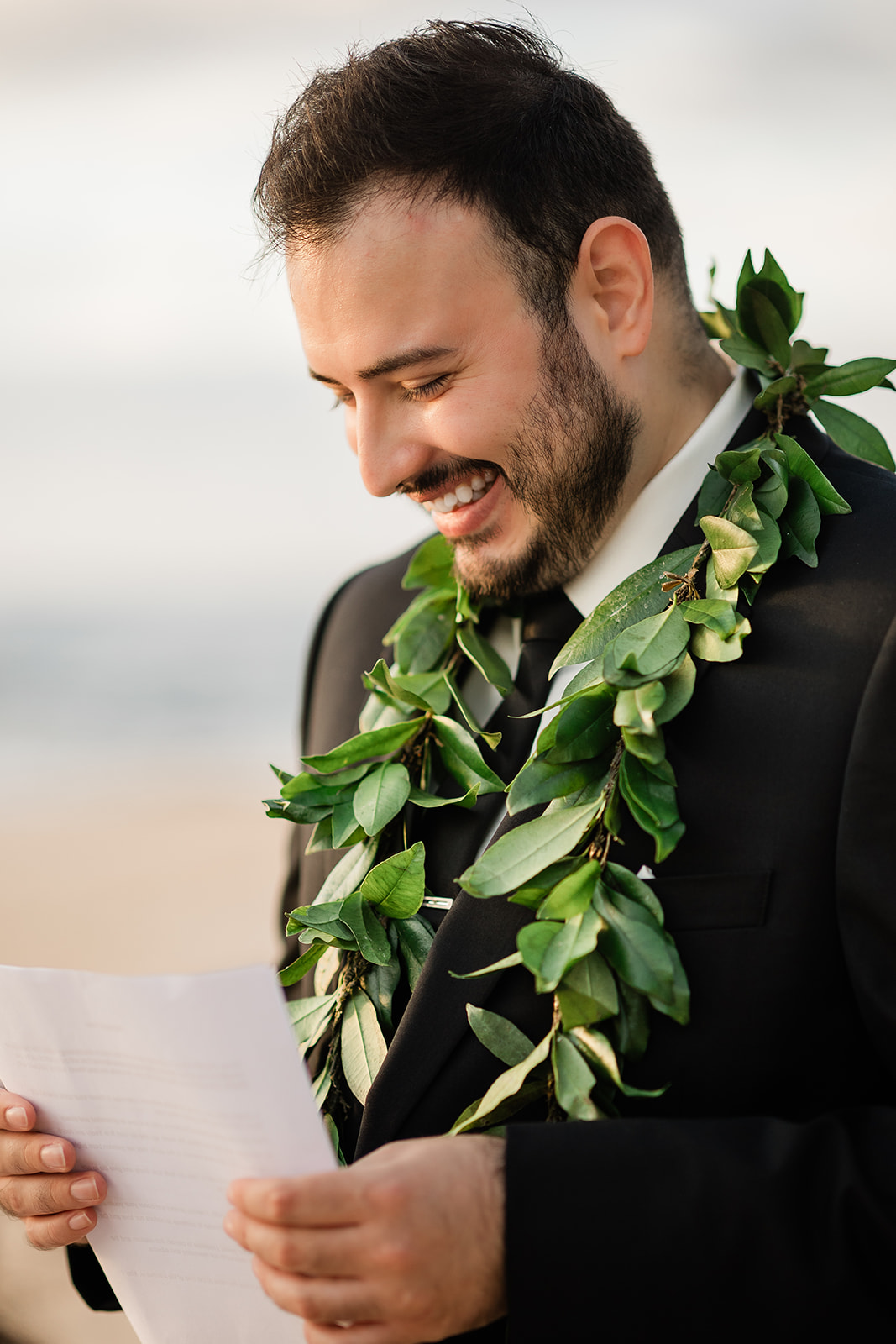 Groom smiling while reading his vows during a beach elopement